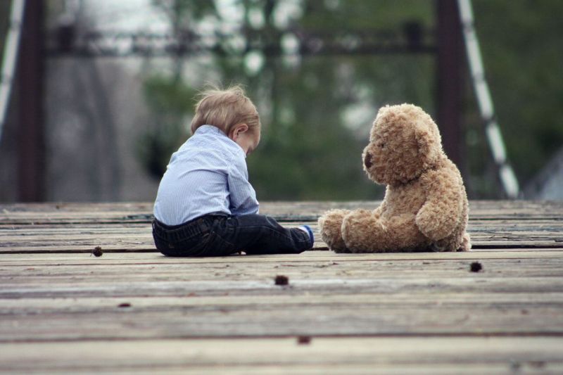 Samotne dziecko i miś na drewnianym pomoście.